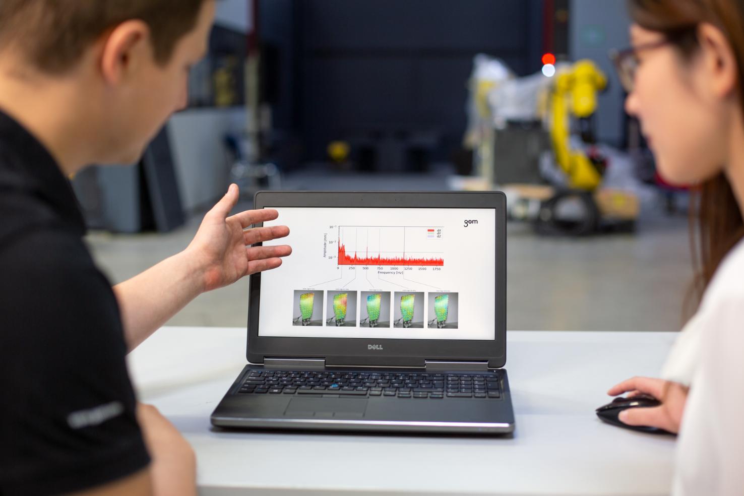 Two additive manufacturing engineers go over an ARAMIS data review on a laptop