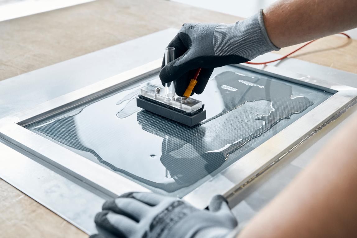 Qualified chemical engineer wearing personal protective equipment uses chemicals to etch sheet metal in a laboratory 